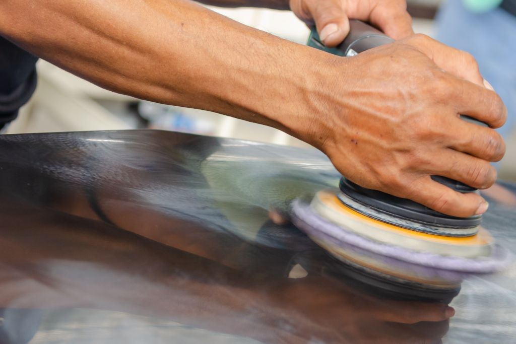 A technician carefully polishes a vehicle’s surface with a rotary buffer, ensuring the finish is smooth and free of imperfections during the preparation for ceramic coating.