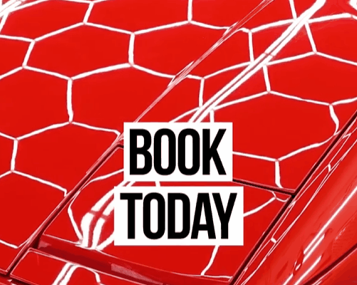 A red car surface with a glossy ceramic coating reflecting bright hexagonal lights, overlaid with bold text that reads "BOOK TODAY," emphasizing the call to action.
