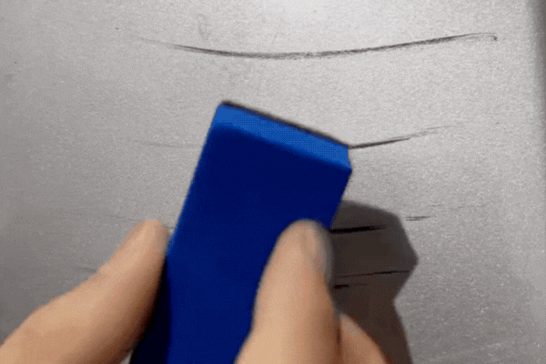 Close-up of a hand holding a blue applicator demonstrating attempts to remove deep scratches from a car's surface, visually addressing the question, "Is Ceramic Coating Scratch-Proof."
