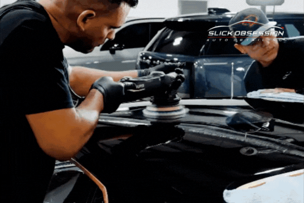 Two technicians at Slick Obsession Auto Detailing in Birmingham AL apply professional ceramic coating using a dual-action polisher inside a controlled shop environment. Demonstrates expert prep and precision in the comparison of DIY vs Professional Ceramic Coating.