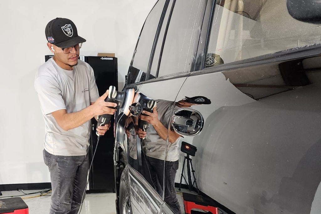 A technician at Slick Obsession Auto Detailing uses a dual-action polisher on a black SUV, preparing the surface for ceramic coating. The highly reflective paintwork highlights expert detailing that impacts Ceramic Coating Cost in Birmingham, AL.