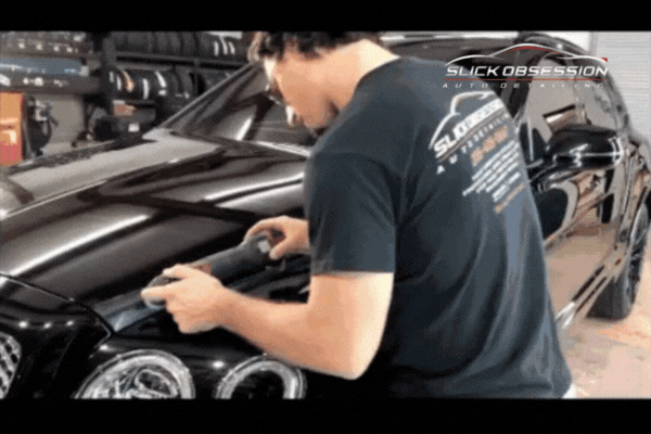 GIF of a Slick Obsession Auto Detailing technician performing a paint correction on a black luxury vehicle inside a Birmingham, AL detailing shop. The video highlights expert craftsmanship and premium care, visually supporting the message to Choose Slick Obsession for superior ceramic coating services.